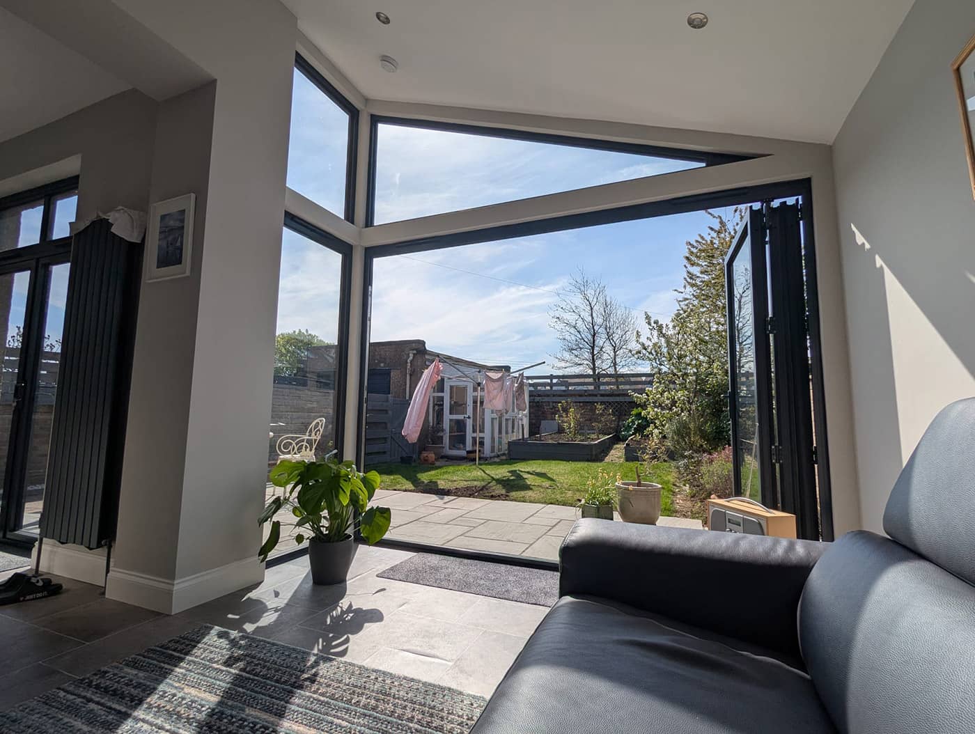 View from inside the completed extension through the glazed corner and open bi-fold doors to the garden