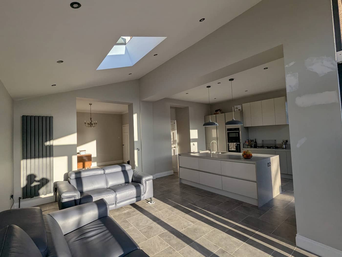 Completed extension with a vaulted ceiling and roof light, and a wide opening through to the kitchen with the beam above boxed in